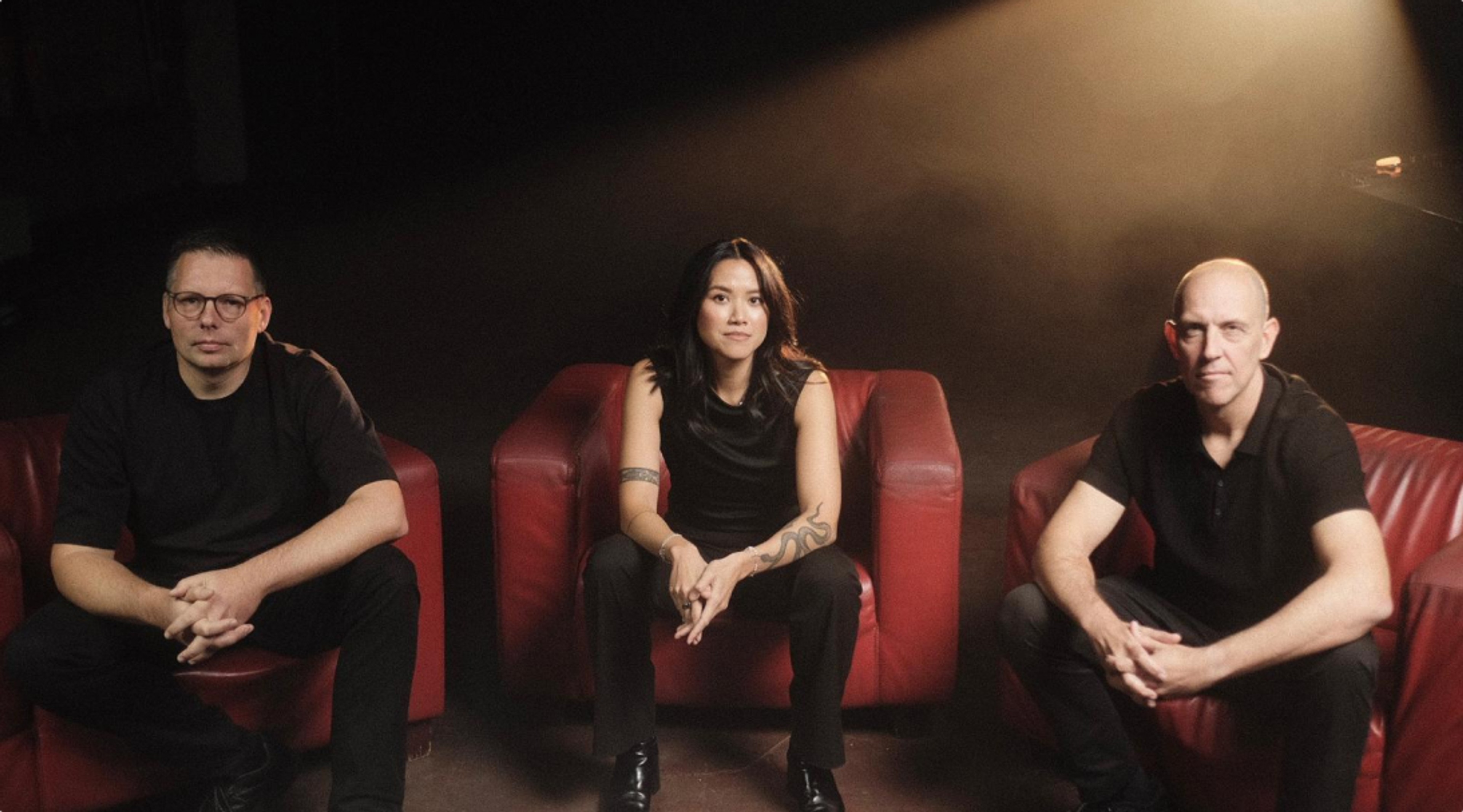 Three A11 team members seated on red armchairs.